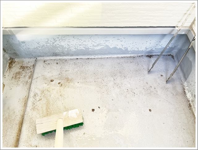 デッキブラシでベランダの床をゴシゴシこすって汚れを取る