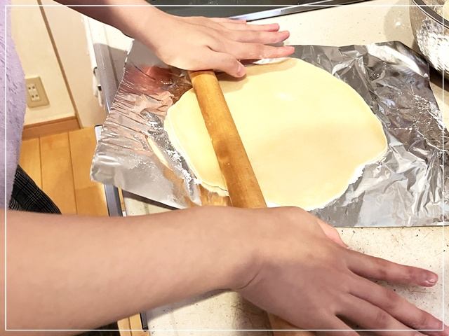 手作りピザの生地をのばす娘